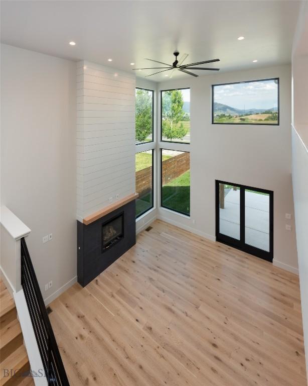 1440 Ryun Sun Way, Bozeman, MT 59718 - unfurnished living room featuring a large fireplace, light wood-type flooring, a ceiling fan, and recessed lighting