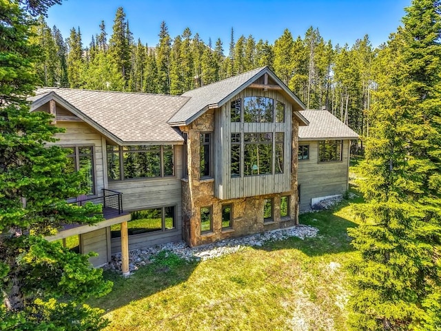 83 Peaks View Dr, Big Sky, MT 59718 - view of front of home featuring a front yard, a shingled roof, and a forest view