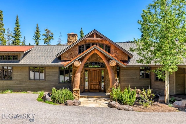 83 Peaks View Dr, Big Sky, MT 59718 - view of front of home with a chimney, stone siding, and a shingled roof