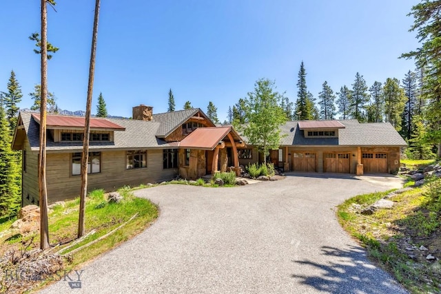 83 Peaks View Dr, Big Sky, MT 59718 - view of front of house featuring driveway, a chimney, and a garage