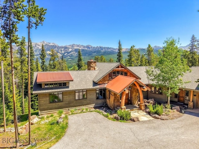 83 Peaks View Dr, Big Sky, MT 59718 - view of front facade featuring a mountain view, stone siding, a chimney, and asphalt driveway