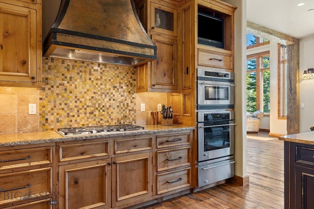 83 Peaks View Dr, Big Sky, MT 59718 - kitchen with custom exhaust hood, a warming drawer, stainless steel appliances, decorative backsplash, and wood finished floors