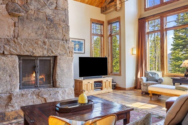 83 Peaks View Dr, Big Sky, MT 59718 - living area with wood finished floors, high vaulted ceiling, a warm lit fireplace, and wood ceiling