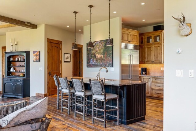 83 Peaks View Dr, Big Sky, MT 59718 - kitchen with stainless steel built in fridge, wood finished floors, recessed lighting, a kitchen bar, and an island with sink