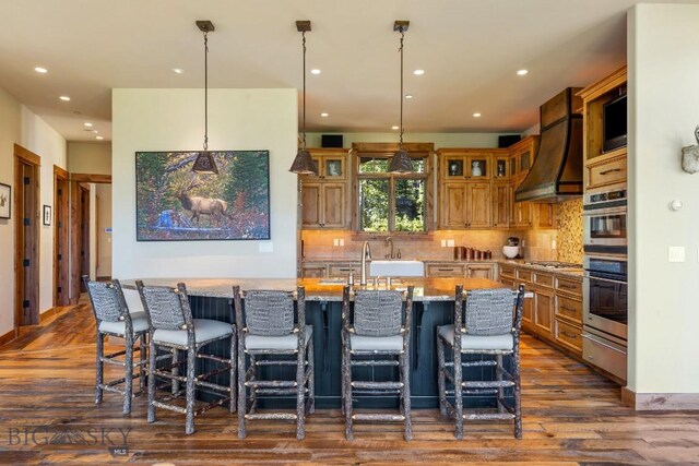 83 Peaks View Dr, Big Sky, MT 59718 - kitchen with dark wood finished floors, appliances with stainless steel finishes, recessed lighting, an island with sink, and a breakfast bar area