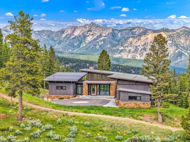 93 Goshawk Trl, Big Sky, MT 59716 - rear view of house featuring a mountain view, a chimney, a patio area, a standing seam roof, and a metal roof