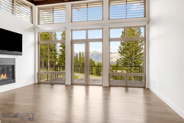 93 Goshawk Trl, Big Sky, MT 59716 - doorway to outside with plenty of natural light, a mountain view, a towering ceiling, and a glass covered fireplace