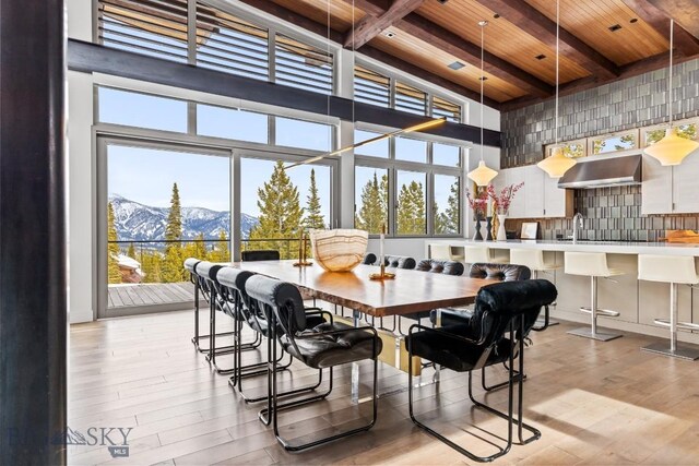 93 Goshawk Trl, Big Sky, MT 59716 - dining room with a mountain view, a wood ceiling with exposed beams, a high ceiling, light wood-style flooring, and plenty of natural light