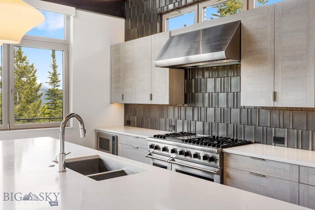 93 Goshawk Trl, Big Sky, MT 59716 - kitchen featuring double oven range, wall chimney range hood, plenty of natural light, and light countertops