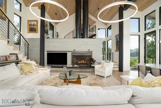 225 Alpen Strasse St, Bozeman, MT 59715 - living area featuring high vaulted ceiling, healthy amount of natural light, a warm lit fireplace, wood finished floors, and stairway