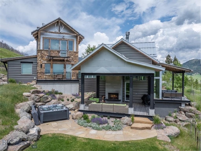 225 Alpen Strasse St, Bozeman, MT 59715 - back of property with an outdoor living space with a fireplace, stone siding, a patio, and a mountain view
