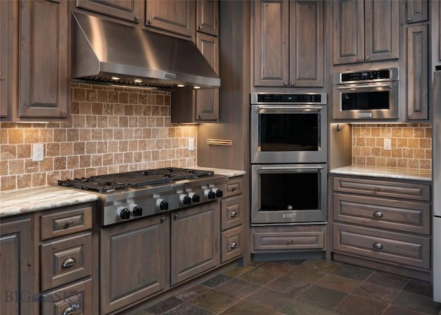 661 Doney Way, Bozeman, MT 59718 - kitchen with extractor fan, stainless steel appliances, light countertops, dark stone finish flooring, and decorative backsplash