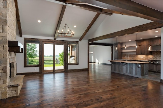 661 Doney Way, Bozeman, MT 59718 - unfurnished living room with a chandelier, beam ceiling, dark wood-style flooring, high vaulted ceiling, and a stone fireplace