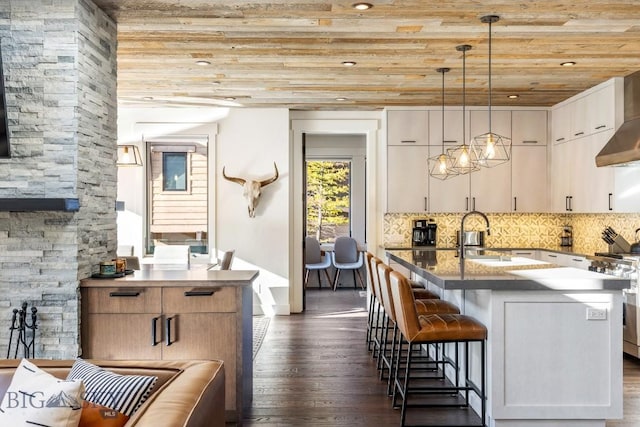 425 Outlook Trl, Big Sky, MT 59716 - kitchen featuring stainless steel gas range oven, dark wood finished floors, a kitchen breakfast bar, wall chimney range hood, and pendant lighting