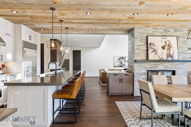 425 Outlook Trl, Big Sky, MT 59716 - kitchen with built in refrigerator, wooden ceiling, dark wood-style floors, white cabinets, and a stone fireplace