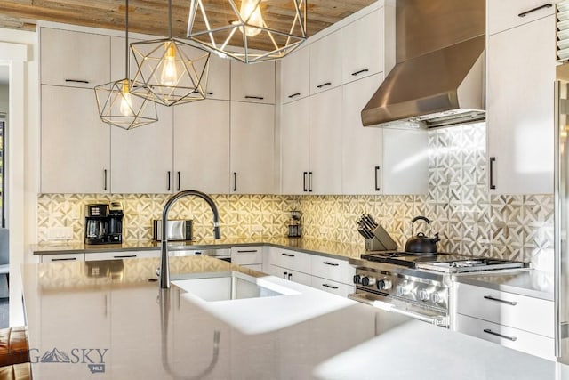 425 Outlook Trl, Big Sky, MT 59716 - kitchen featuring wall chimney range hood, stainless steel stove, hanging light fixtures, and decorative backsplash