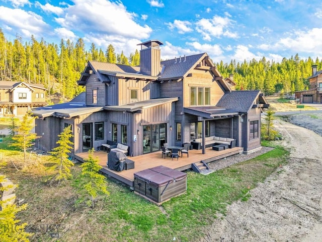 425 Outlook Trl, Big Sky, MT 59716 - back of property with outdoor lounge area, a chimney, a deck, board and batten siding, and roof with shingles
