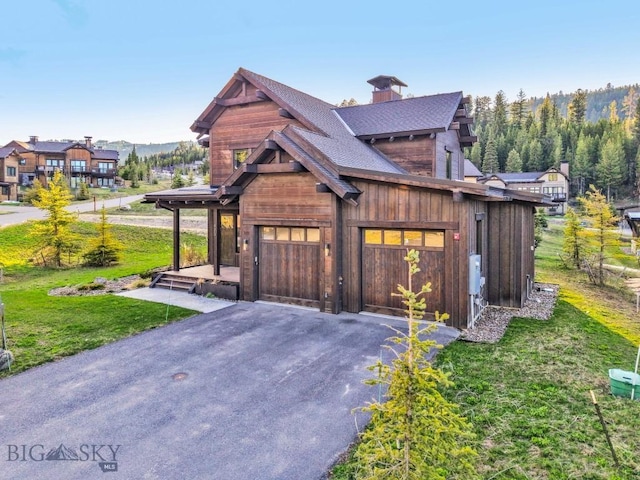 425 Outlook Trl, Big Sky, MT 59716 - view of front of house featuring asphalt driveway, a front yard, a chimney, roof with shingles, and a garage