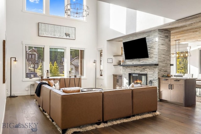 425 Outlook Trl, Big Sky, MT 59716 - living room featuring a towering ceiling, a chandelier, a stone fireplace, wood finished floors, and healthy amount of natural light