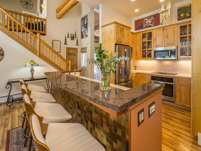 80 Crail Creek Ct Unit 616, Big Sky, MT 59716 - kitchen featuring appliances with stainless steel finishes, light wood-style floors, recessed lighting, tasteful backsplash, and a kitchen bar