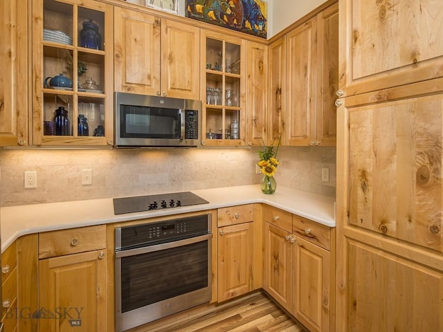 80 Crail Creek Ct Unit 616, Big Sky, MT 59716 - kitchen with appliances with stainless steel finishes, decorative backsplash, light countertops, glass insert cabinets, and light wood finished floors