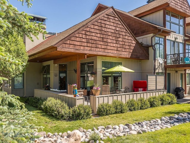 80 Crail Creek Ct Unit 616, Big Sky, MT 59716 - rear view of house featuring a yard, a shingled roof, and a porch