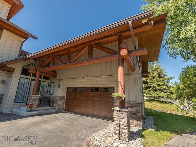 80 Crail Creek Ct Unit 616, Big Sky, MT 59716 - view of front of house featuring stone siding, driveway, board and batten siding, and a garage