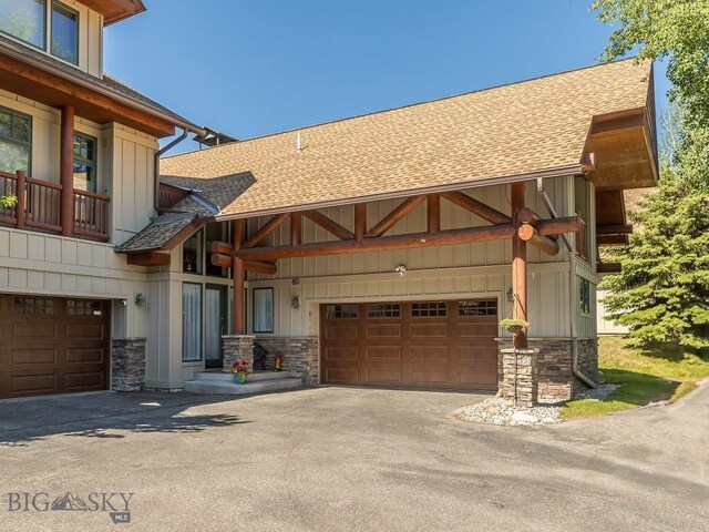 80 Crail Creek Ct Unit 616, Big Sky, MT 59716 - view of front of house featuring roof with shingles, stone siding, and driveway