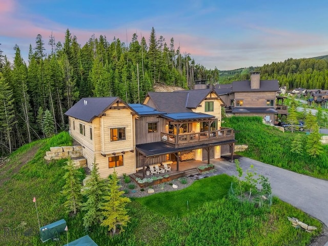 580 Outlook Trl Unit 42, Big Sky, MT 59730 - back of house at dusk featuring a garage, driveway, a deck, a lawn, and a chimney