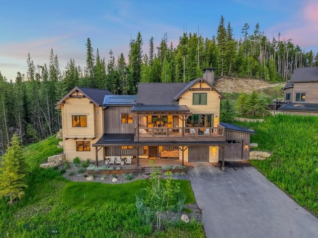 580 Outlook Trl Unit 42, Big Sky, MT 59730 - back of house featuring an attached garage, a balcony, asphalt driveway, a chimney, and a view of trees