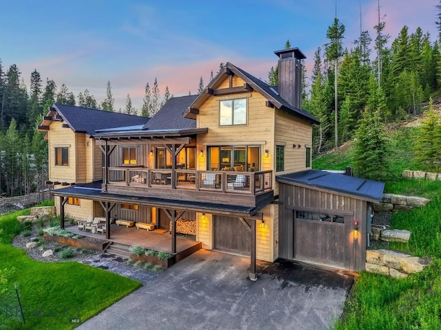 580 Outlook Trl Unit 42, Big Sky, MT 59730 - rear view of house with an attached garage, driveway, a chimney, a wooden deck, and a shingled roof