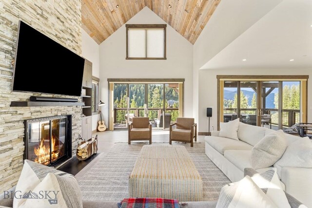 580 Outlook Trl Unit 42, Big Sky, MT 59730 - living area featuring a stone fireplace, wood ceiling, healthy amount of natural light, high vaulted ceiling, and light wood-style flooring