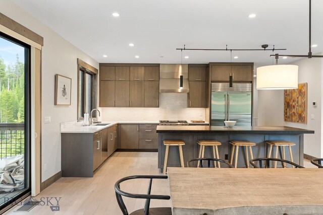 580 Outlook Trl Unit 42, Big Sky, MT 59730 - kitchen with built in fridge, wall chimney exhaust hood, modern cabinets, a breakfast bar, and recessed lighting