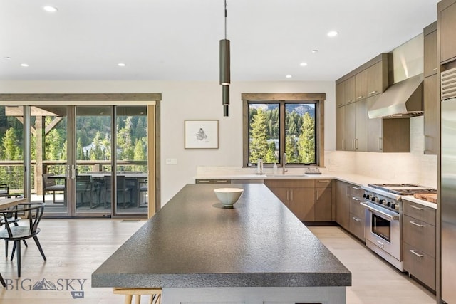 580 Outlook Trl Unit 42, Big Sky, MT 59730 - kitchen with stainless steel stove, wall chimney exhaust hood, recessed lighting, healthy amount of natural light, and light wood-style floors