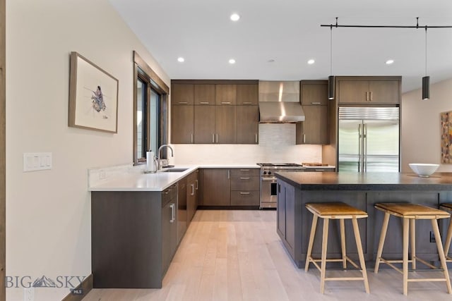 580 Outlook Trl Unit 42, Big Sky, MT 59730 - kitchen with high quality appliances, wall chimney range hood, a breakfast bar, recessed lighting, and light wood-style floors