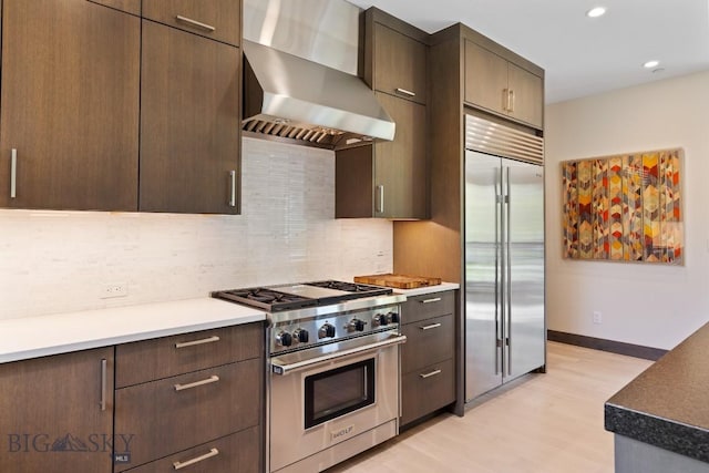 580 Outlook Trl Unit 42, Big Sky, MT 59730 - kitchen with high quality appliances, wall chimney range hood, light wood-type flooring, backsplash, and dark brown cabinetry