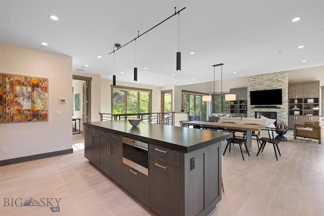 580 Outlook Trl Unit 42, Big Sky, MT 59730 - kitchen with dark countertops, light wood-type flooring, recessed lighting, a stone fireplace, and a large island