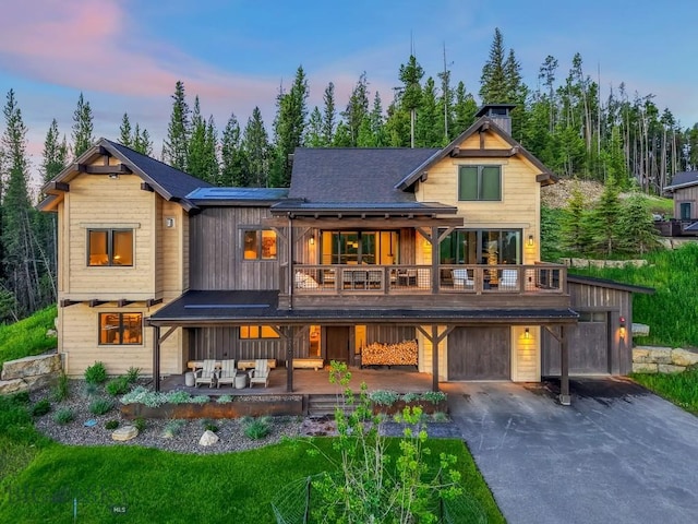 580 Outlook Trl Unit 42, Big Sky, MT 59730 - back of property at dusk featuring a balcony, concrete driveway, an outdoor living space, and a chimney