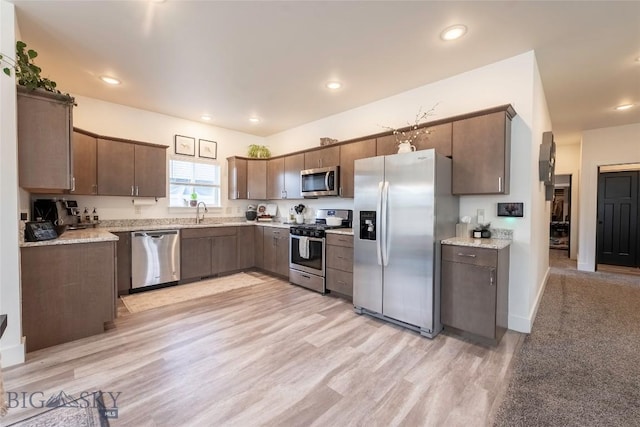 1306 Scooter Ln, Belgrade, MT 59714 - kitchen with appliances with stainless steel finishes, light wood-type flooring, recessed lighting, dark brown cabinets, and light stone countertops
