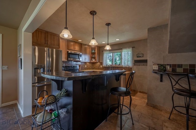 302 Ordway St S, Wilsall, MT 59086 - kitchen with stainless steel appliances, brown cabinetry, dark countertops, glass insert cabinets, and a kitchen bar