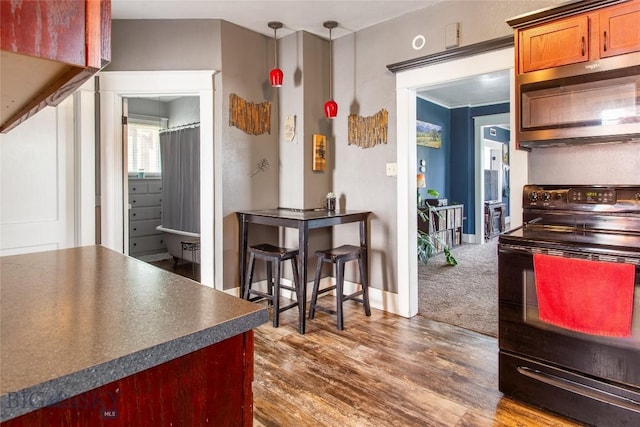 221 E Front, Butte, MT 59701 - kitchen featuring black electric range, stainless steel microwave, dark countertops, dark wood-type flooring, and brown cabinetry