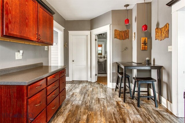 221 E Front, Butte, MT 59701 - kitchen featuring dark wood finished floors, dark countertops, reddish brown cabinets, and decorative light fixtures
