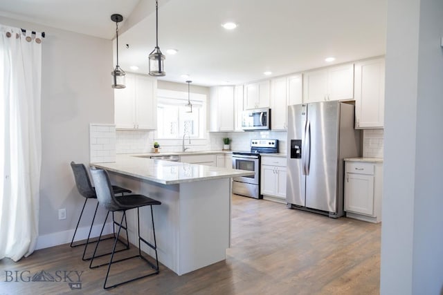138 E Shade Tree Ln, Manhattan, MT 59741 - kitchen featuring appliances with stainless steel finishes, a peninsula, white cabinets, tasteful backsplash, and recessed lighting