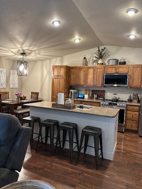 86 Tail Feather Unit C, Bozeman, MT 59718 - kitchen featuring appliances with stainless steel finishes, a kitchen bar, brown cabinets, dark wood-style flooring, and recessed lighting
