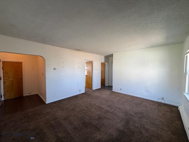 1915 S Montana, Butte, MT 59701 - carpeted spare room with a baseboard radiator, a textured ceiling, and arched walkways