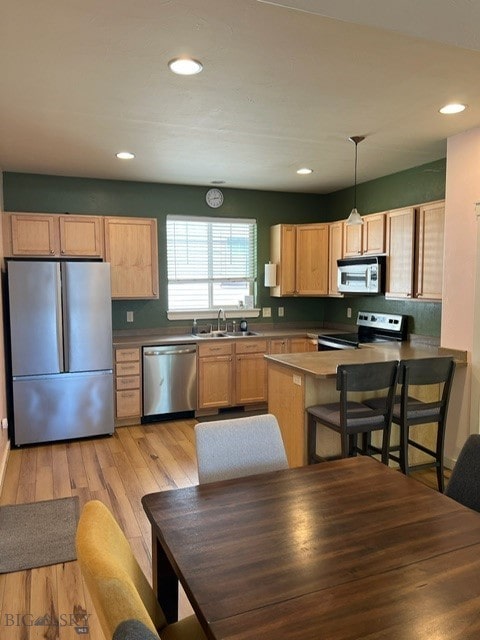 3885 Equestrian Ln, Bozeman, MT 59718 - kitchen with appliances with stainless steel finishes, light wood-style floors, a peninsula, recessed lighting, and light brown cabinetry