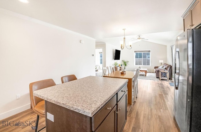 708 Pierre St, Belgrade, MT 59714 - kitchen with freestanding refrigerator, a breakfast bar area, open floor plan, a kitchen island, and crown molding