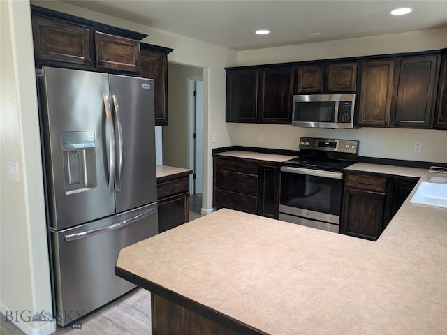 477 W River Rock, Belgrade, MT 59714 - kitchen with appliances with stainless steel finishes, dark brown cabinetry, light countertops, recessed lighting, and light wood-style floors