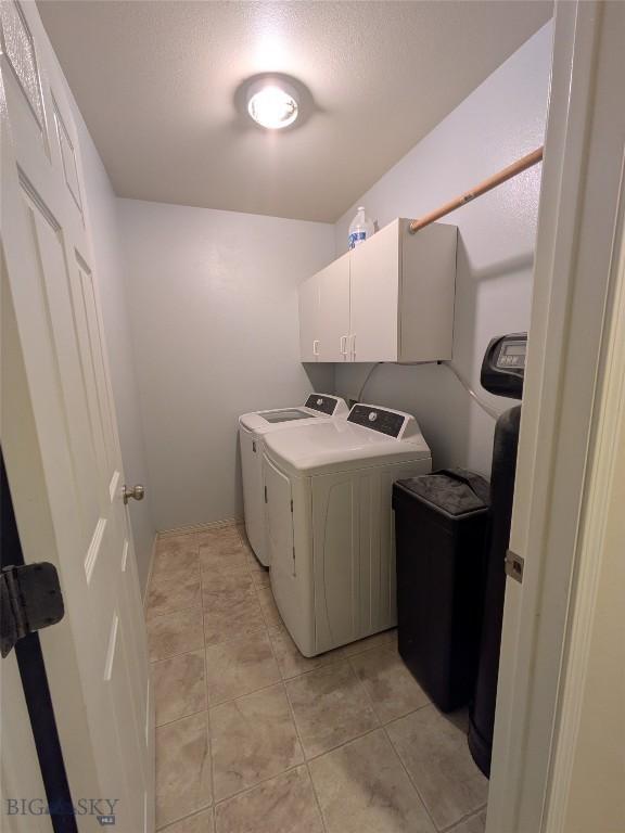 477 W River Rock, Belgrade, MT 59714 - laundry area with washer and dryer, cabinet space, light tile patterned floors, and a textured ceiling