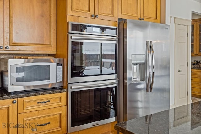 3609 Fieldstone W, Bozeman, MT 59715 - kitchen with appliances with stainless steel finishes, dark stone counters, and brown cabinets